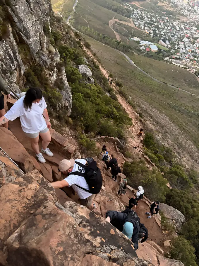 Wanderer steigen bei Dämmerung über steile Felsstufen den Lion's Head hinab