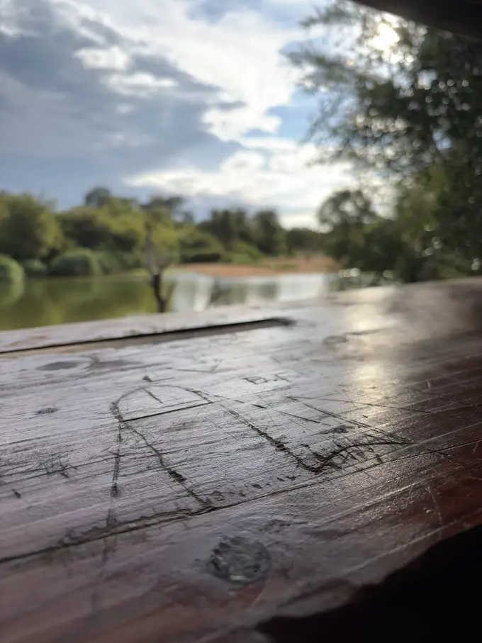 Holzterrasse mit Geländer über einem ruhigen Fluss, Bäume am gegenüberliegenden Ufer