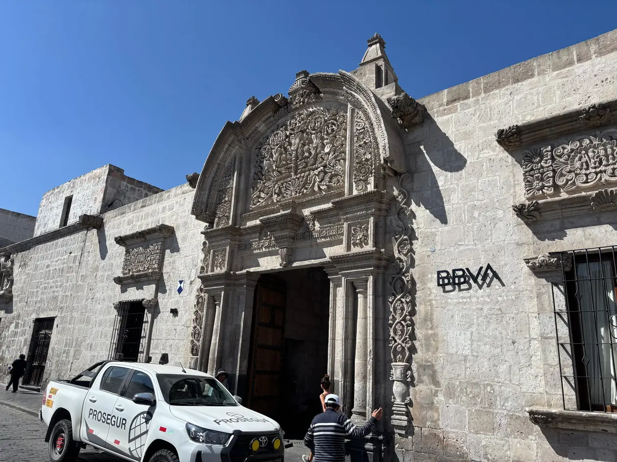 Kolonialhaus aus hellem Stein mit reich verziertem Barockportal an einer Straßenecke, davor ein weißer Pick-up