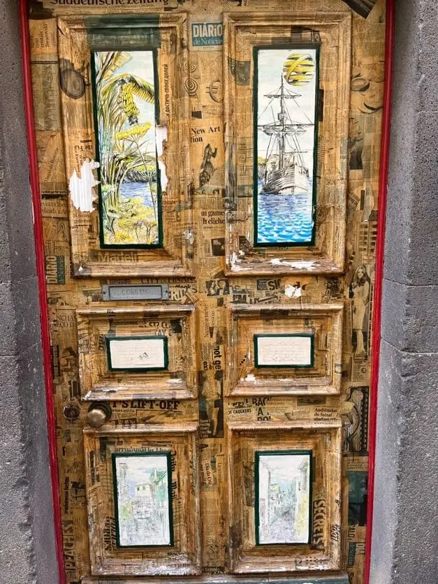 Bemalte Holztür mit Feldern aus Zeitungsausschnitten und Segelschiff-Motiven
