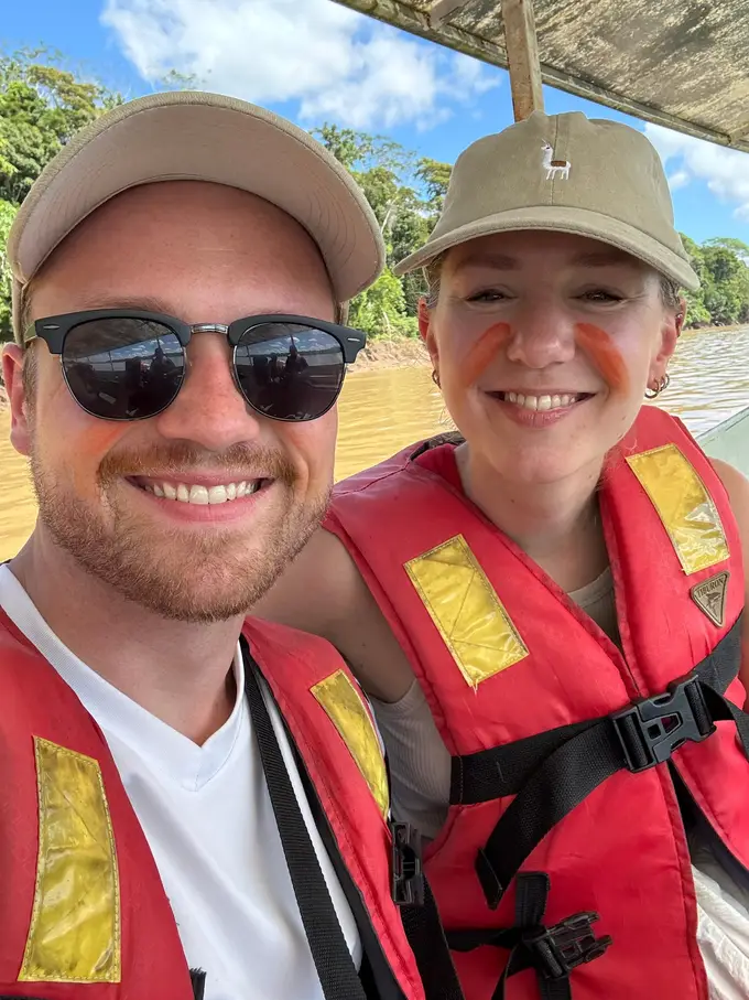 Selfie von Max und Rebecca im Boot in Schwimmwesten, Rebecca hat rot-orange Striche auf den Wangen