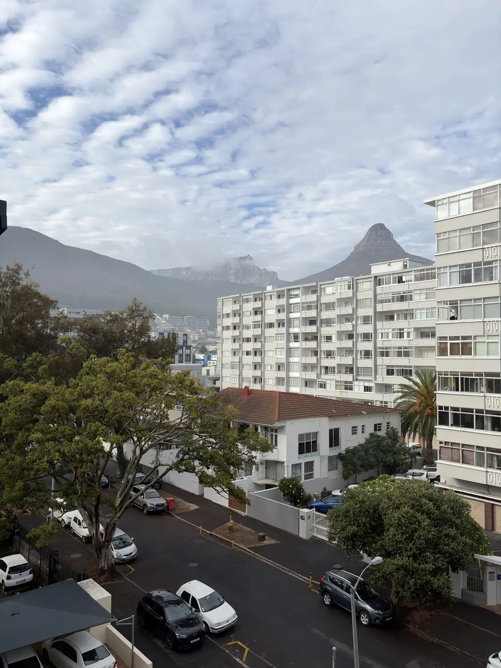 Ausblick von einem hohen Fenster über die Dächer von Sea Point Richtung Lion's Head im morgendlichen Dunst