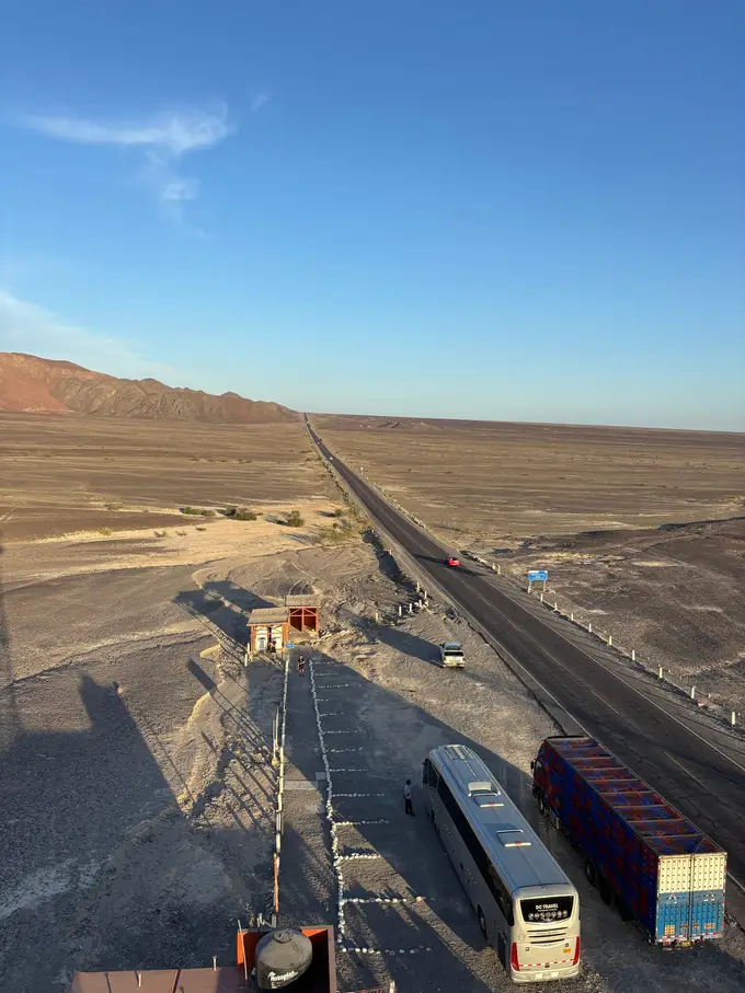 Blick von oben auf die Panamericana, einen Reisebus und einen Lkw am Fuß des Aussichtsturms, rechts und links Wüste