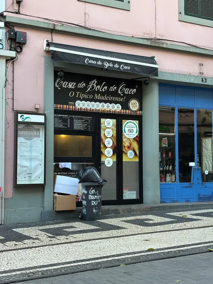Beleuchtete Ladenfront eines Bolo-do-Caco-Geschäfts in einer Gasse am Abend