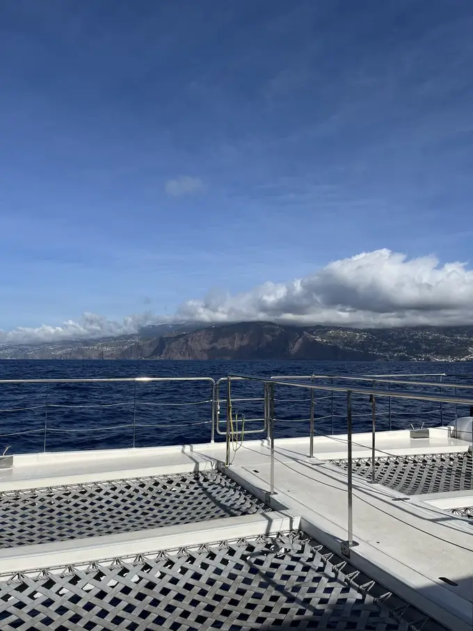 Blick vom Bug eines Katamarans auf das offene Meer mit einer Wolkenbank am Horizont