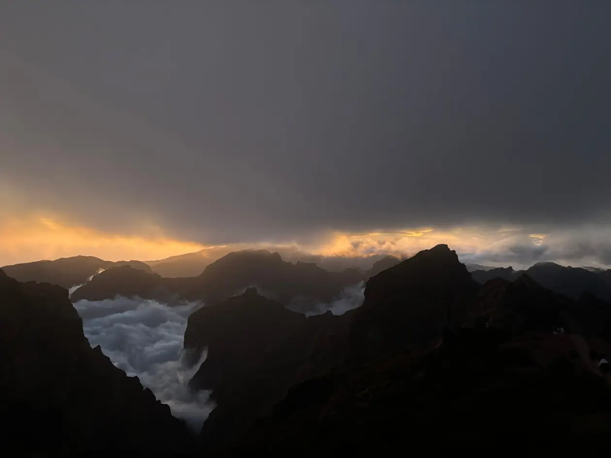 Fast dunkler Himmel mit einem letzten schmalen orangen Streifen über dem Wolkenmeer