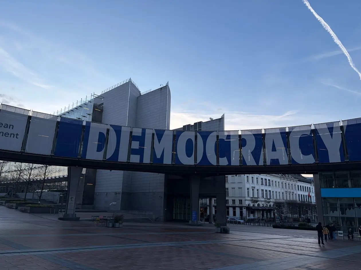 Ein Übergang zwischen den Gebäuden des Europäischen Parlaments, behängt mit einem Banner mit dem Wort Democracy in großen Buchstaben, darunter ein fast leerer Platz