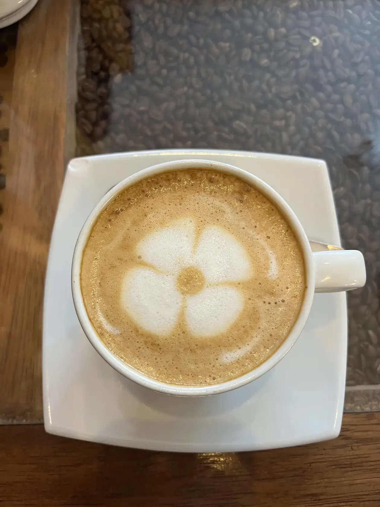 Cappuccino mit einer Blume aus Milchschaum auf einer weißen Untertasse