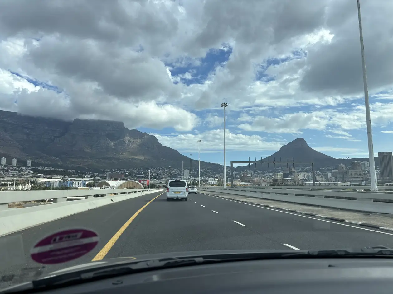 Blick durch die Windschutzscheibe auf eine Stadtautobahn Richtung Kapstadt, im Hintergrund der Lion's Head