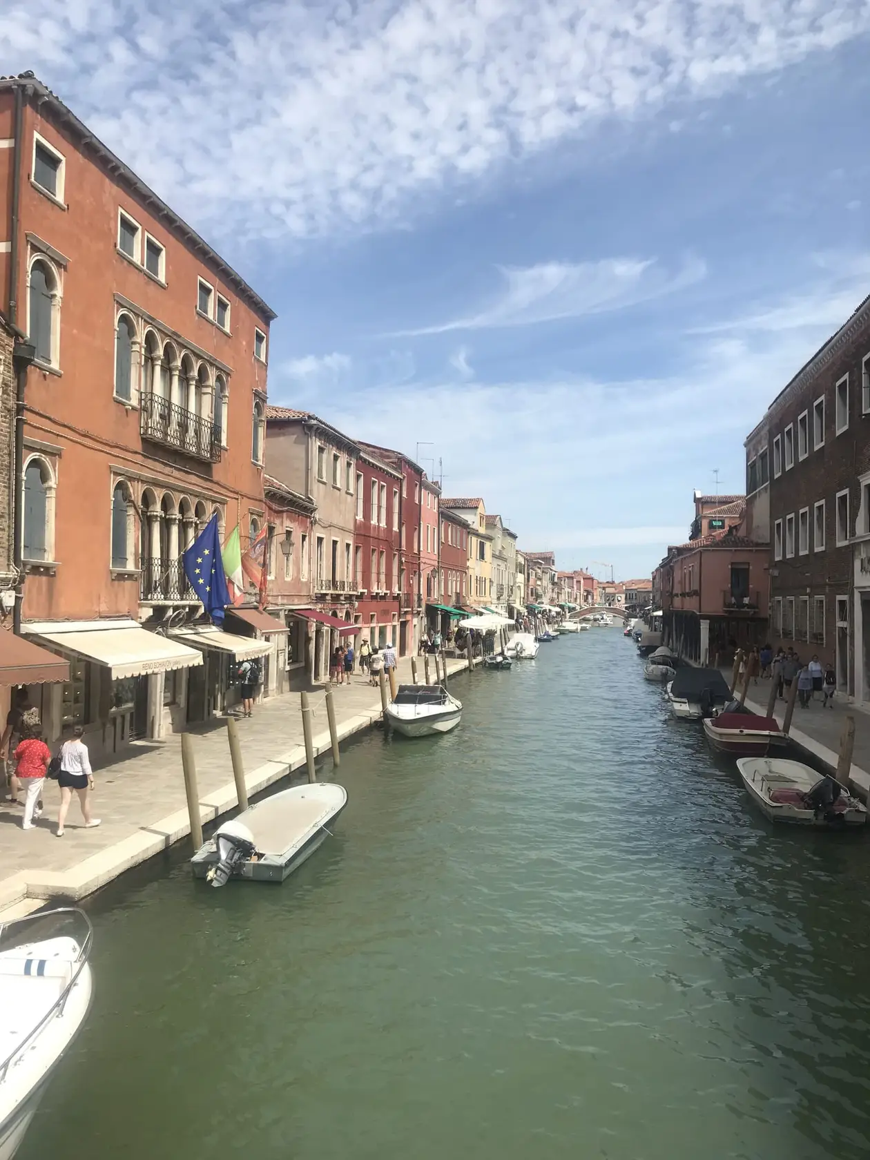 Ein breiter Kanal auf Murano mit Booten, zu beiden Seiten mehrstöckige Häuser in warmen Farben