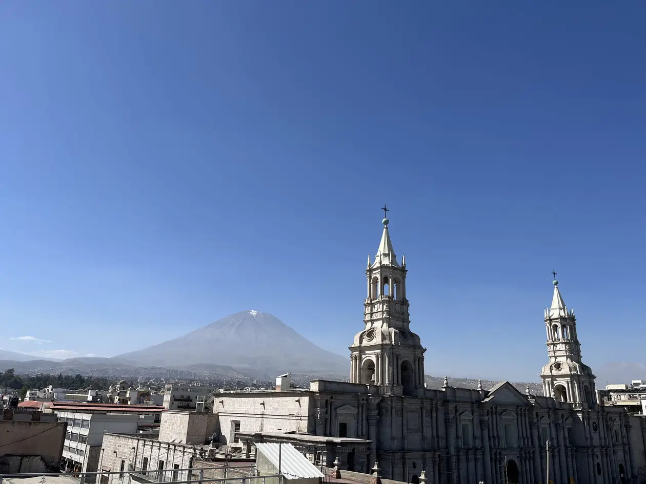 Die beiden Türme der Kathedrale von Arequipa über den Dächern der Stadt, dahinter der kegelförmige Misti