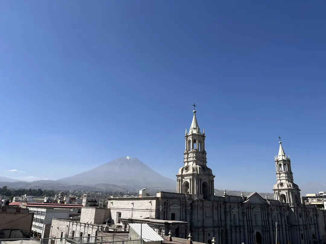 Die beiden Türme der Kathedrale von Arequipa über den Dächern der Stadt, dahinter der kegelförmige Misti