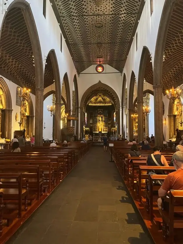 Innenraum einer Kirche mit vergoldetem Altar und Holzbänken