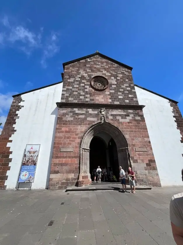Weiße Kirchenfassade mit rotem Ziegelportal und Rosettenfenster