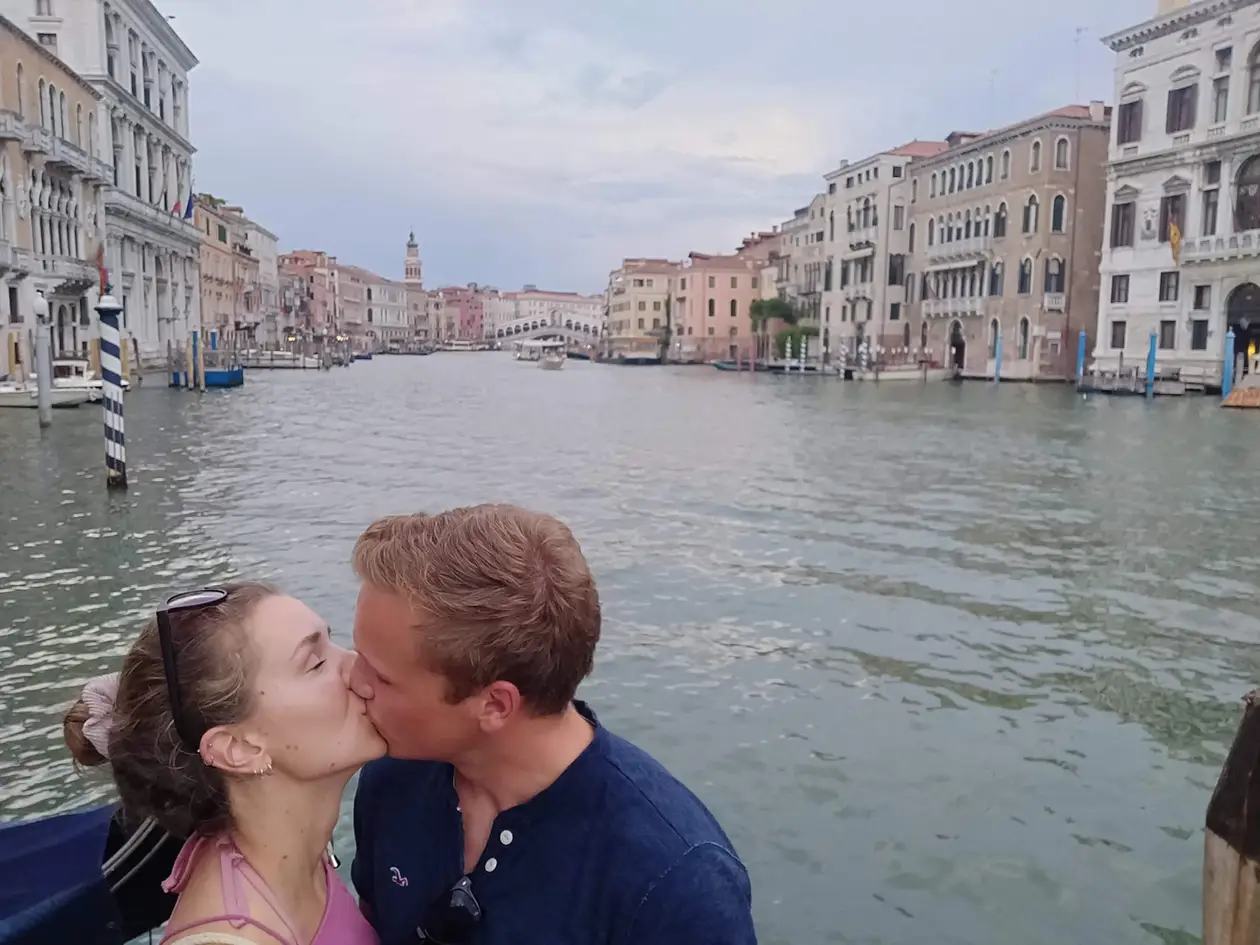 Max und Rebecca küssen sich vor dem Canal Grande, hinter ihnen Paläste und in der Ferne die Rialtobrücke