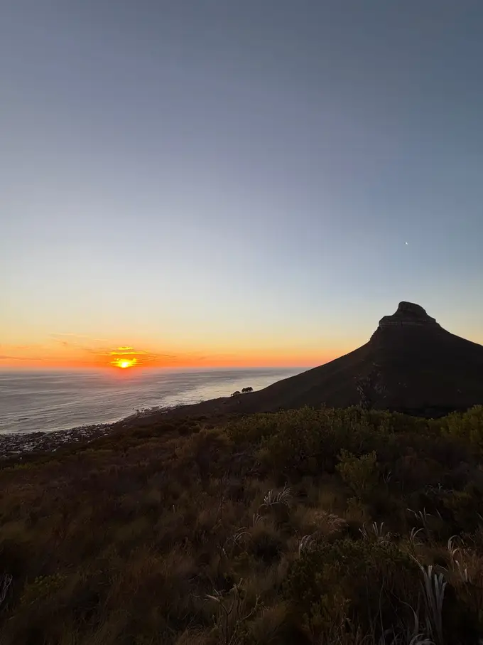 Silhouette des Lion's Head vor einem orange-rosa Sonnenuntergangshimmel über dem Meer