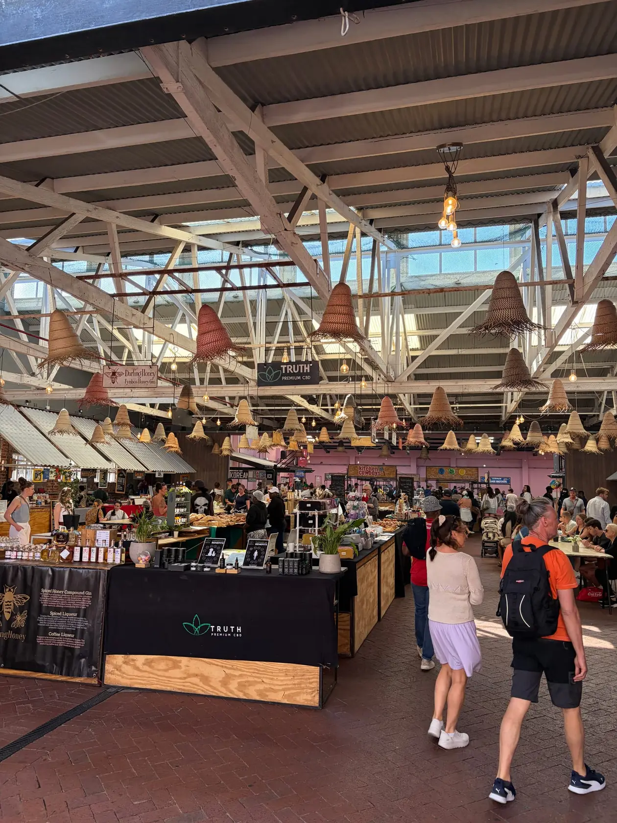 Belebte Markthalle der Old Biscuit Mill mit vielen Menschen an Essensständen unter einem hohen Hallendach