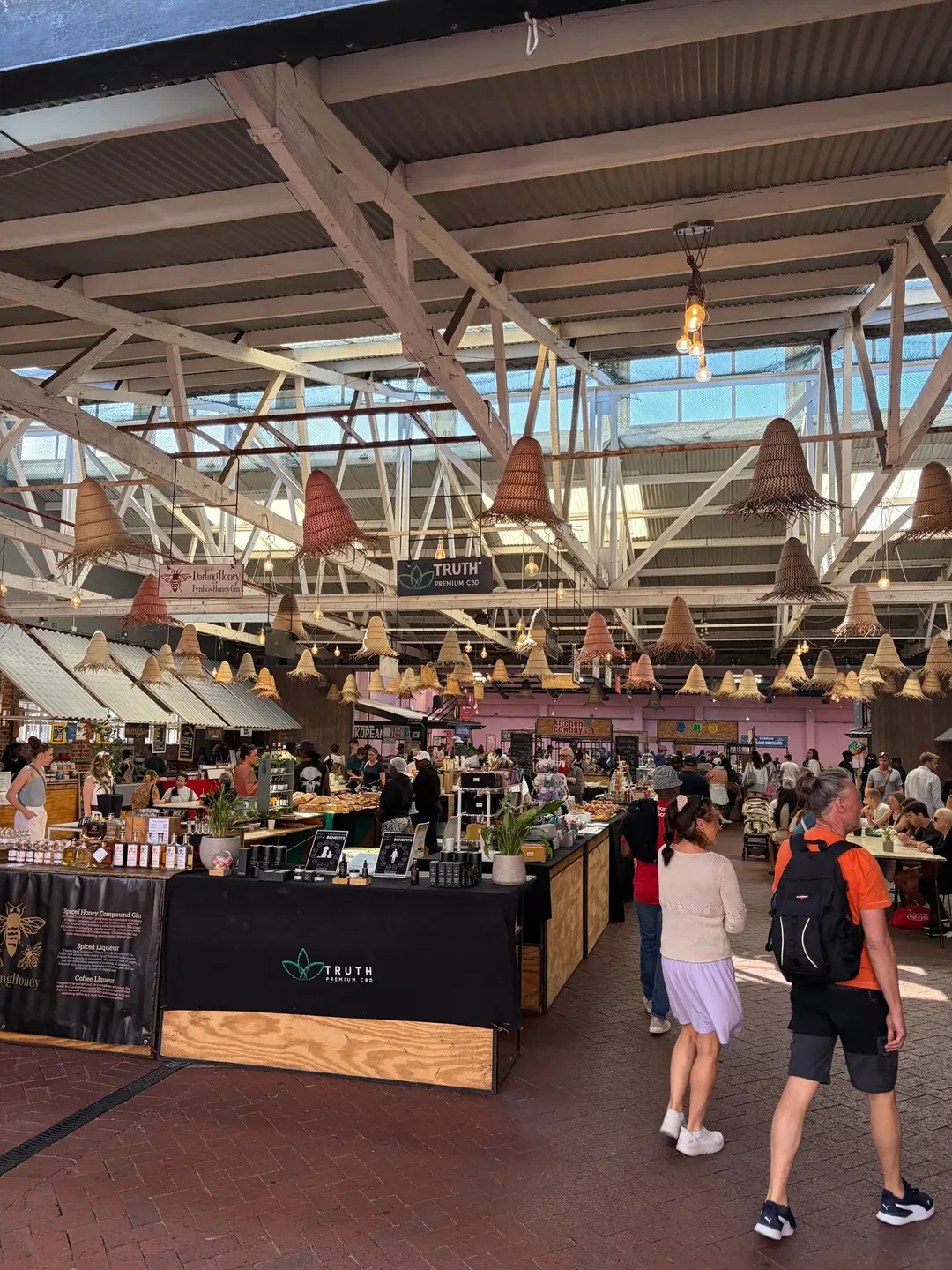 Belebte Markthalle der Old Biscuit Mill mit vielen Menschen an Essensständen unter einem hohen Hallendach