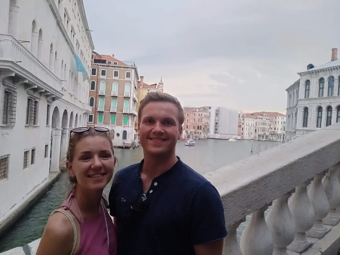 Rebecca und Max an der steinernen Balustrade einer Brücke über dem Canal Grande, hinter ihnen Palastfassaden