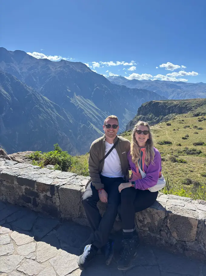 Max und Rebecca sitzen auf einer Steinmauer, hinter ihnen fallen die Hänge des Canyons steil ab