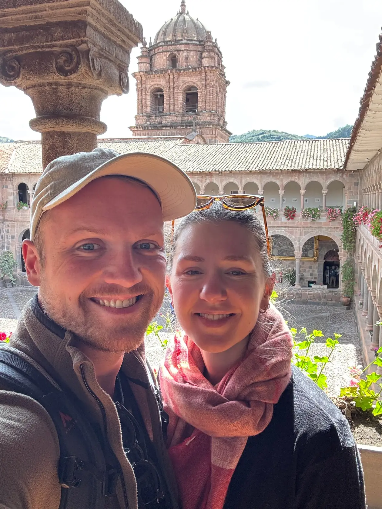 Selfie von Max und Rebecca in einem Kreuzgang mit Arkaden, dahinter ein Kirchturm mit Kuppel