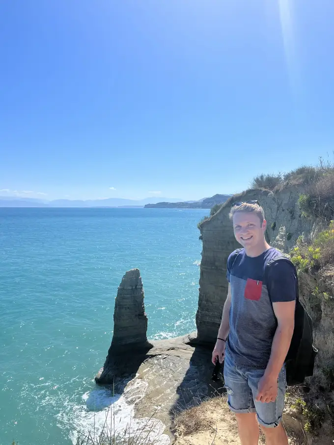 Max steht auf einem Felsvorsprung, hinter ihm eine Felsnadel im Meer