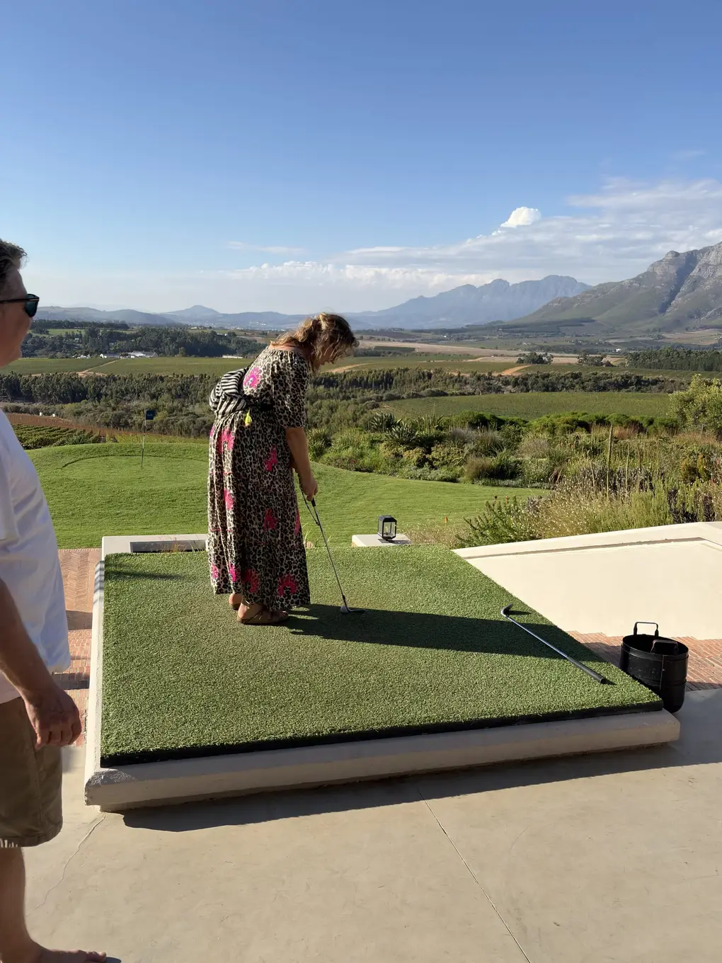 Jana und Lars an der Abschlagstelle, einer von beiden schlägt gerade einen Ball, im Hintergrund das Tal