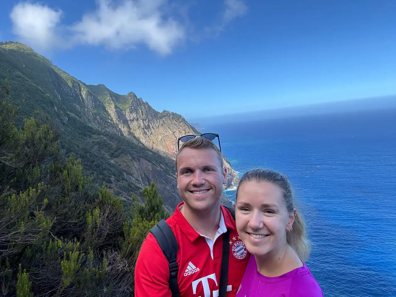 Zwei Personen stehen an einem Klippenrand mit Blick auf die Steilküste und das Meer