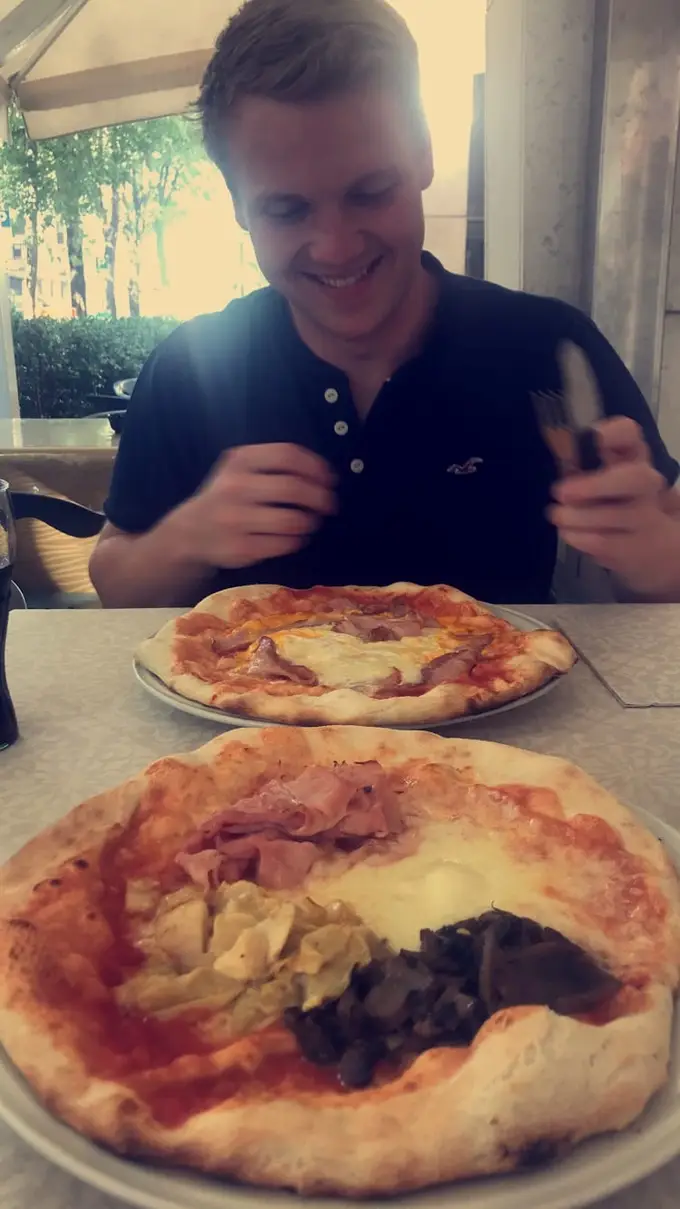 Max schneidet in einem Restaurant eine Pizza an, auf dem Tisch eine zweite Pizza