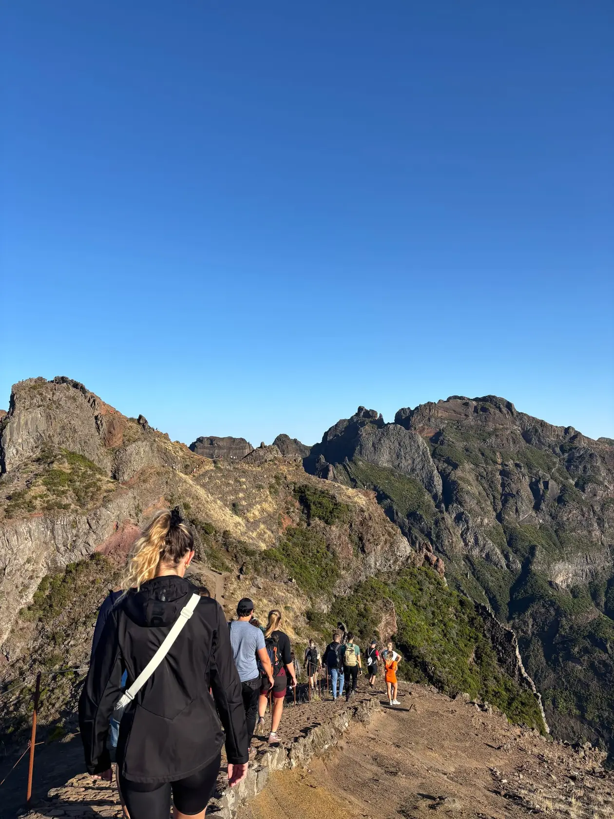 Wanderer auf dem schmalen Gratweg des PR1 zwischen schroffen Felsspitzen