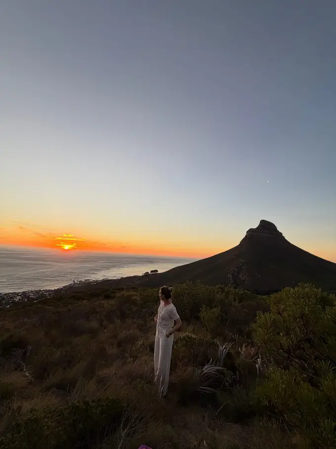 Rebecca steht auf dem Felsvorsprung und blickt auf den Sonnenuntergang über dem Atlantik