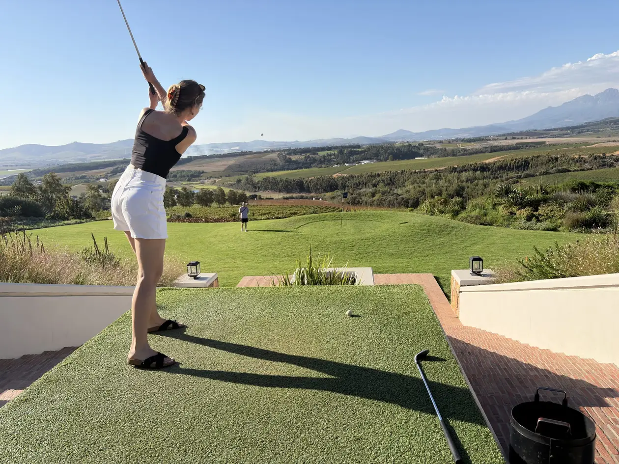 Rebecca mitten im Golfschwung auf der Terrasse, im Hintergrund das weite Tal