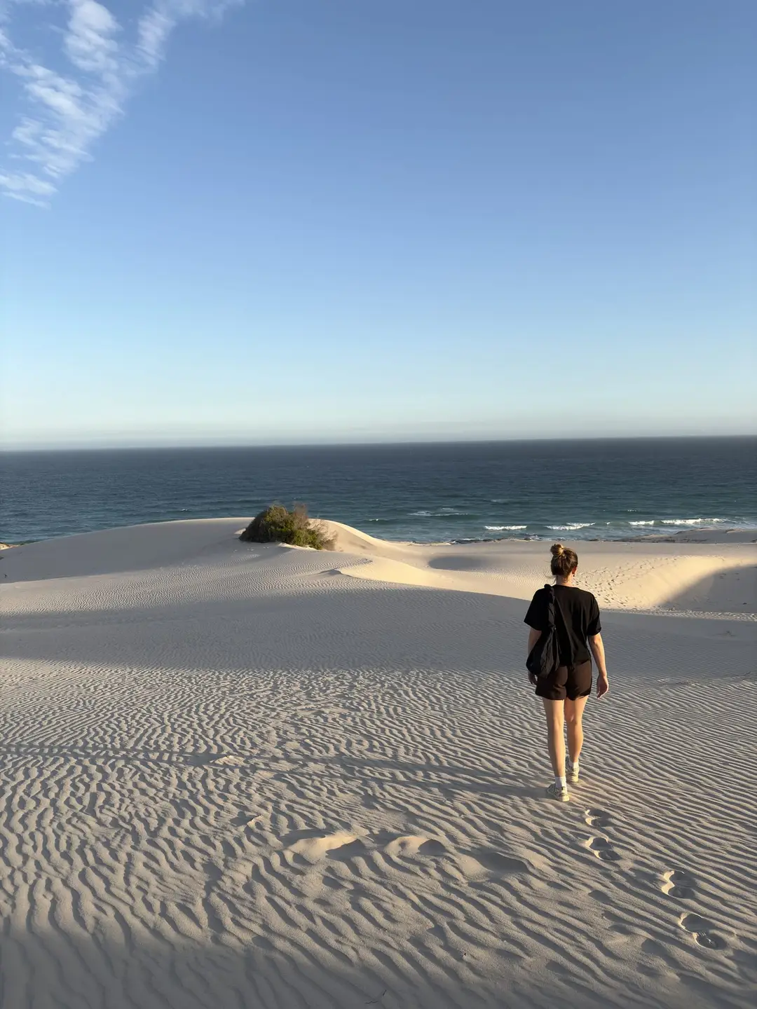 Rebecca läuft allein über eine weiße Sanddüne auf das Meer zu