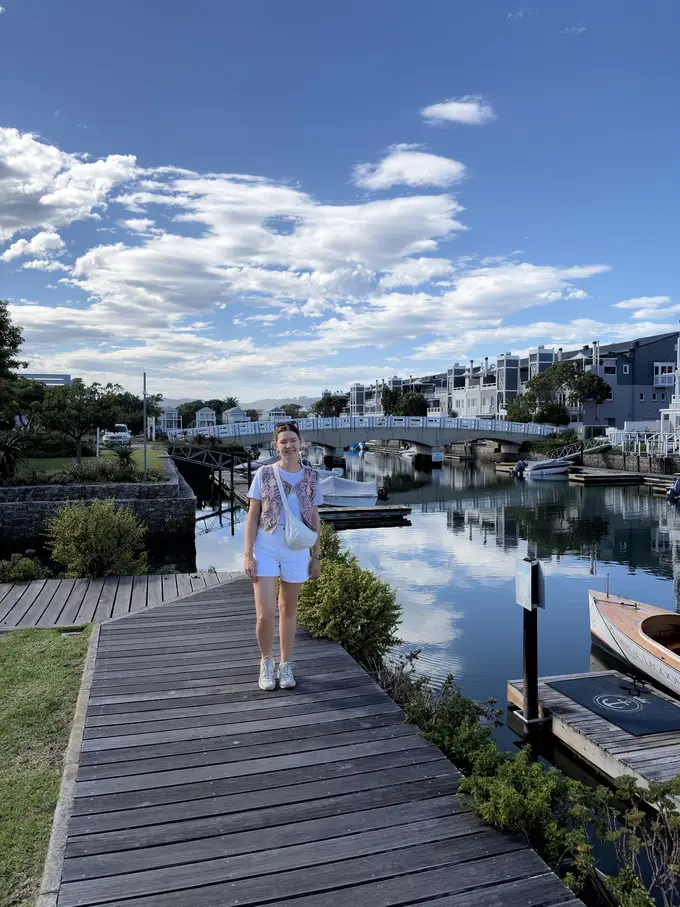 Rebecca steht auf einem Holzsteg am Kanal von Thesen Island, im Hintergrund Boote und Häuser