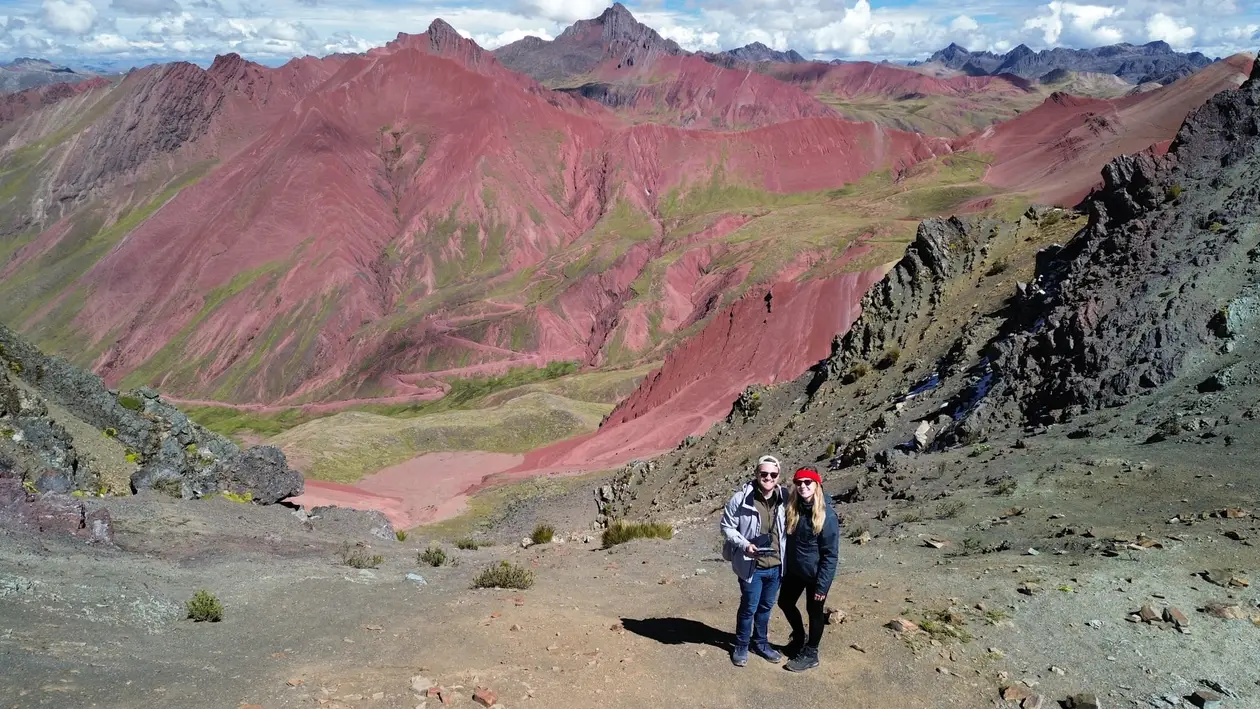 Drohnenblick auf Max und Rebecca, die klein auf einem Geröllhang stehen, hinter ihnen das tiefrot gefärbte Red Valley