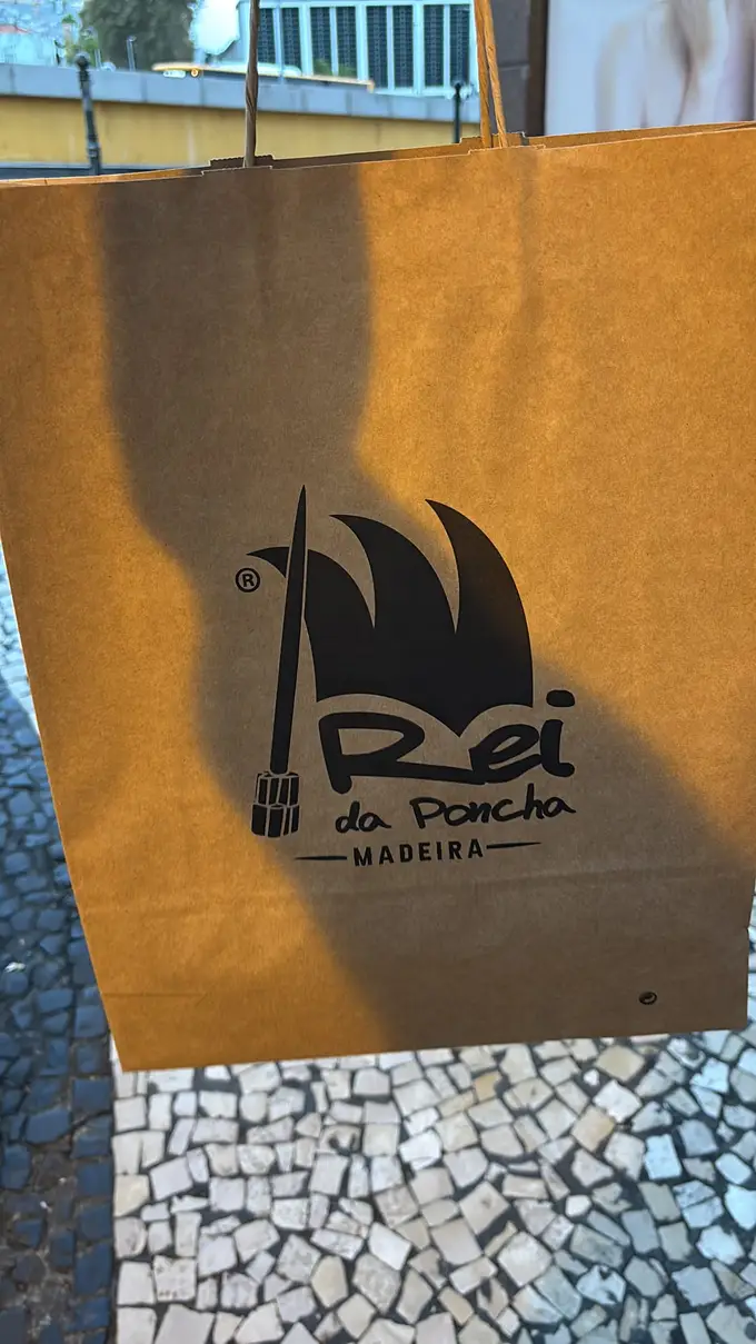 Papiertüte mit dem Logo „Rei da Poncha“ auf Kopfsteinpflaster