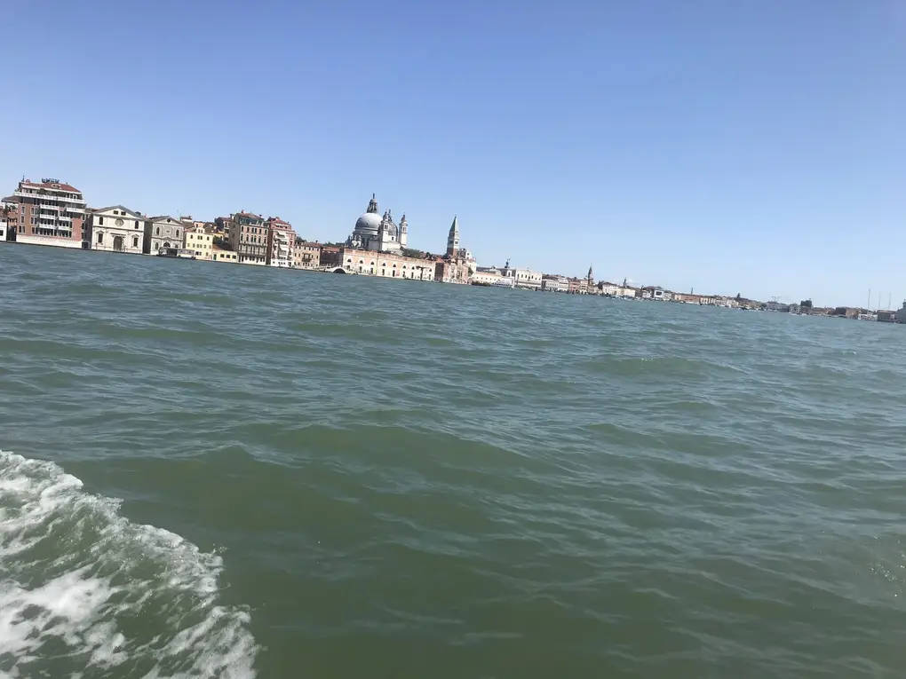 Blick vom Boot über bewegtes Wasser auf die Uferzeile der Altstadt mit der Kuppel der Salute-Kirche