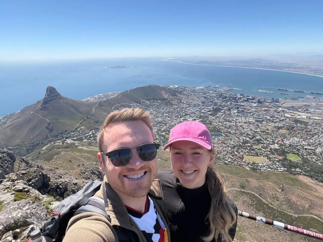 Max und Rebecca machen ein Selfie oben auf dem Tafelberg, im Hintergrund der Lion's Head und die Bucht von Kapstadt