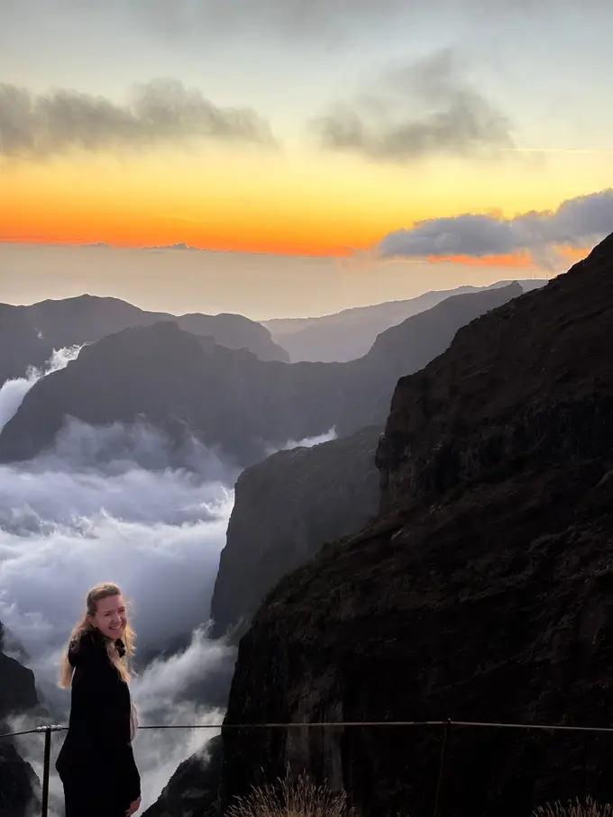 Warmes Abendlicht über dem Wolkenmeer, eine Person schaut zur untergehenden Sonne