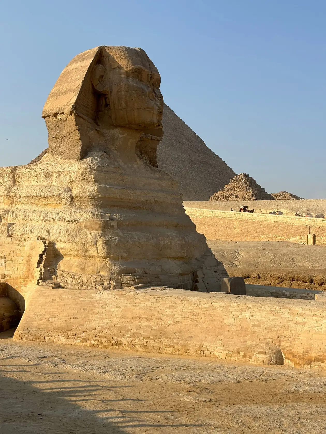 Die Sphinx von der Seite im Nachmittagslicht, dahinter eine große und zwei kleine Pyramiden