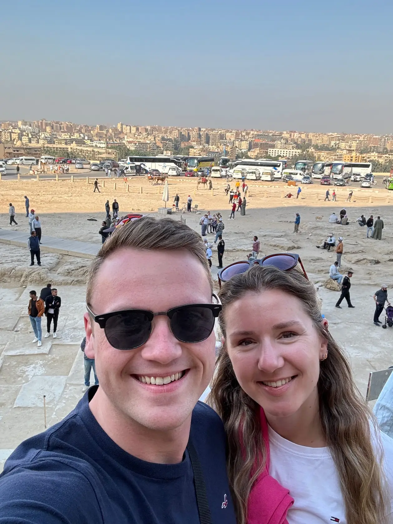 Selfie von Max und Rebecca am Rand des Plateaus, hinter ihnen Besucher, Reisebusse und direkt dahinter die dicht bebaute Stadt