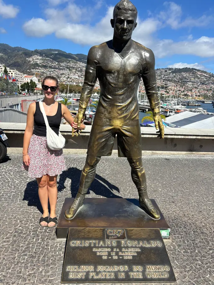 Frau steht lächelnd neben einer bronzenen Cristiano-Ronaldo-Statue auf einem Sockel