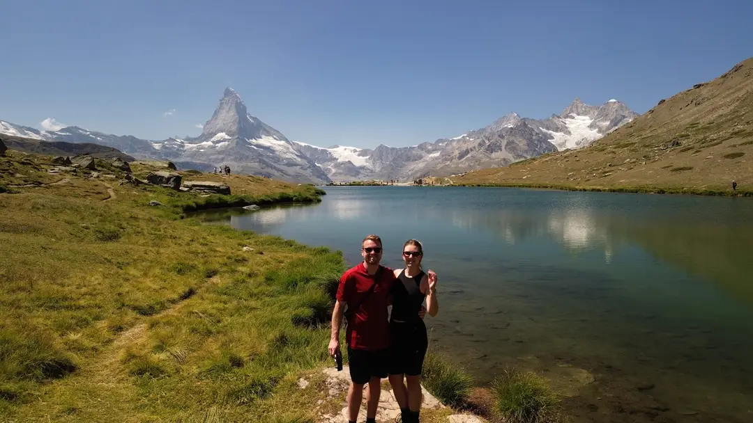 Max und Rebecca am Ufer des Stellisees, hinter ihnen das Matterhorn und verschneite Gipfel, die sich im See spiegeln