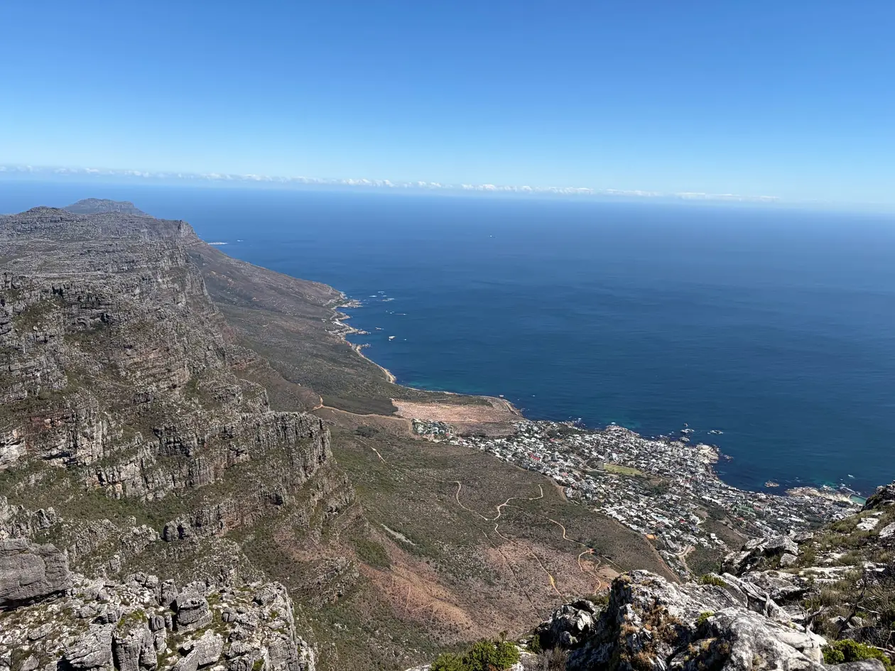 Blick vom Tafelberg auf die zerklüftete Küste und den Atlantik unter blauem Himmel
