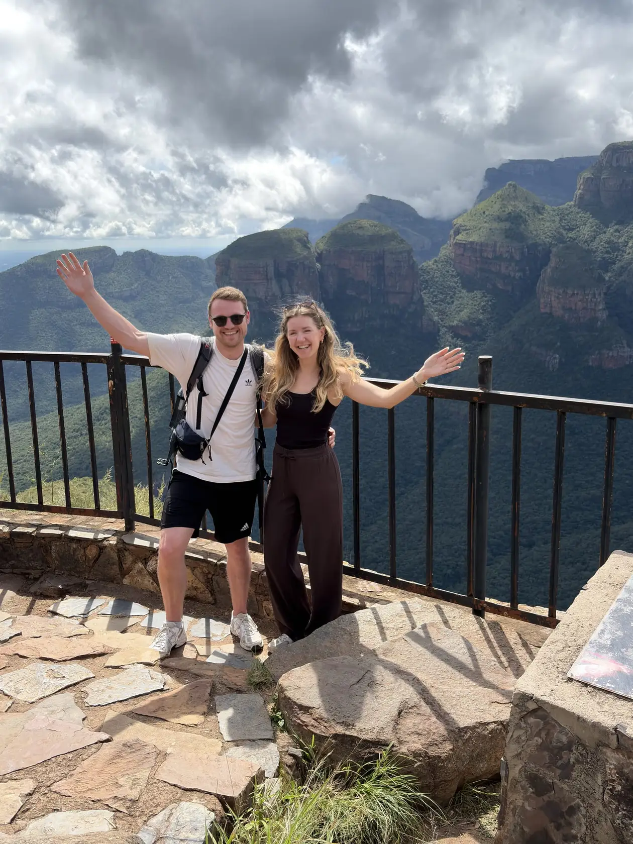 Max und Rebecca winken an einem Aussichtspunkt, dahinter die drei runden Felskuppen der Three Rondavels