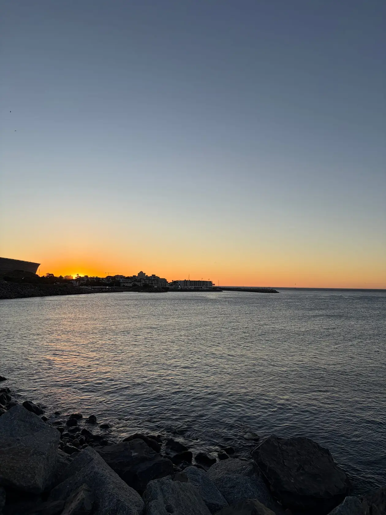 Sonnenuntergang über dem Wasser an der V&A Waterfront, der Himmel orange und rosa gefärbt